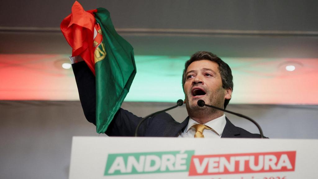El candidato presidencial portugués y líder del partido Chega, André Ventura, sostiene una bandera portuguesa mientras pronuncia un discurso.