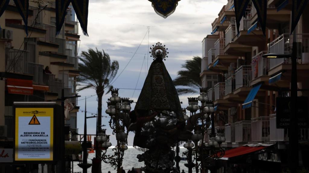 El viento golpea las palmeras con la Virgen del Sufragio en Benidorm.