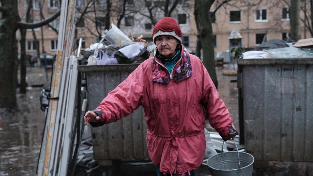 Una residente de Kramatorsk vacía los cubos que ha llenado con los cristales de su casa, bombardeada por Rusia en la mañana del domingo.
