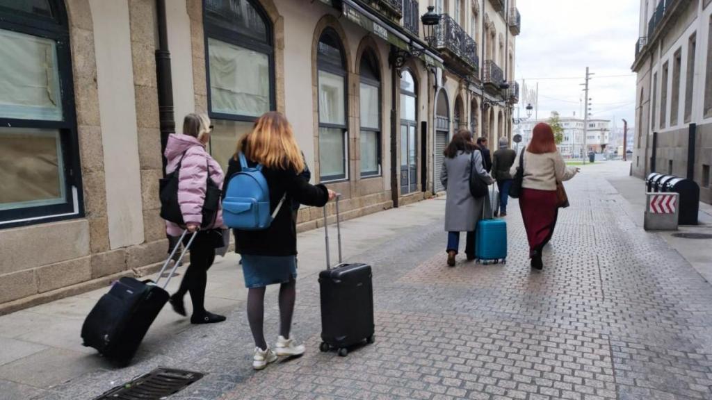 Turistas con maletas caminan por el centro de A Coruña.
