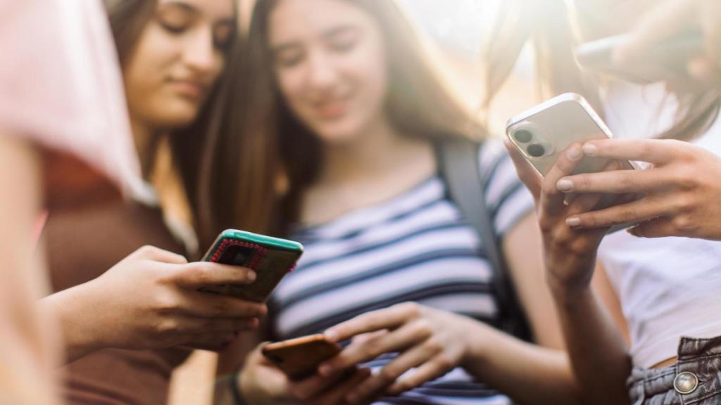 Las adolescentes se divierten y conversan usando sus teléfonos móviles.