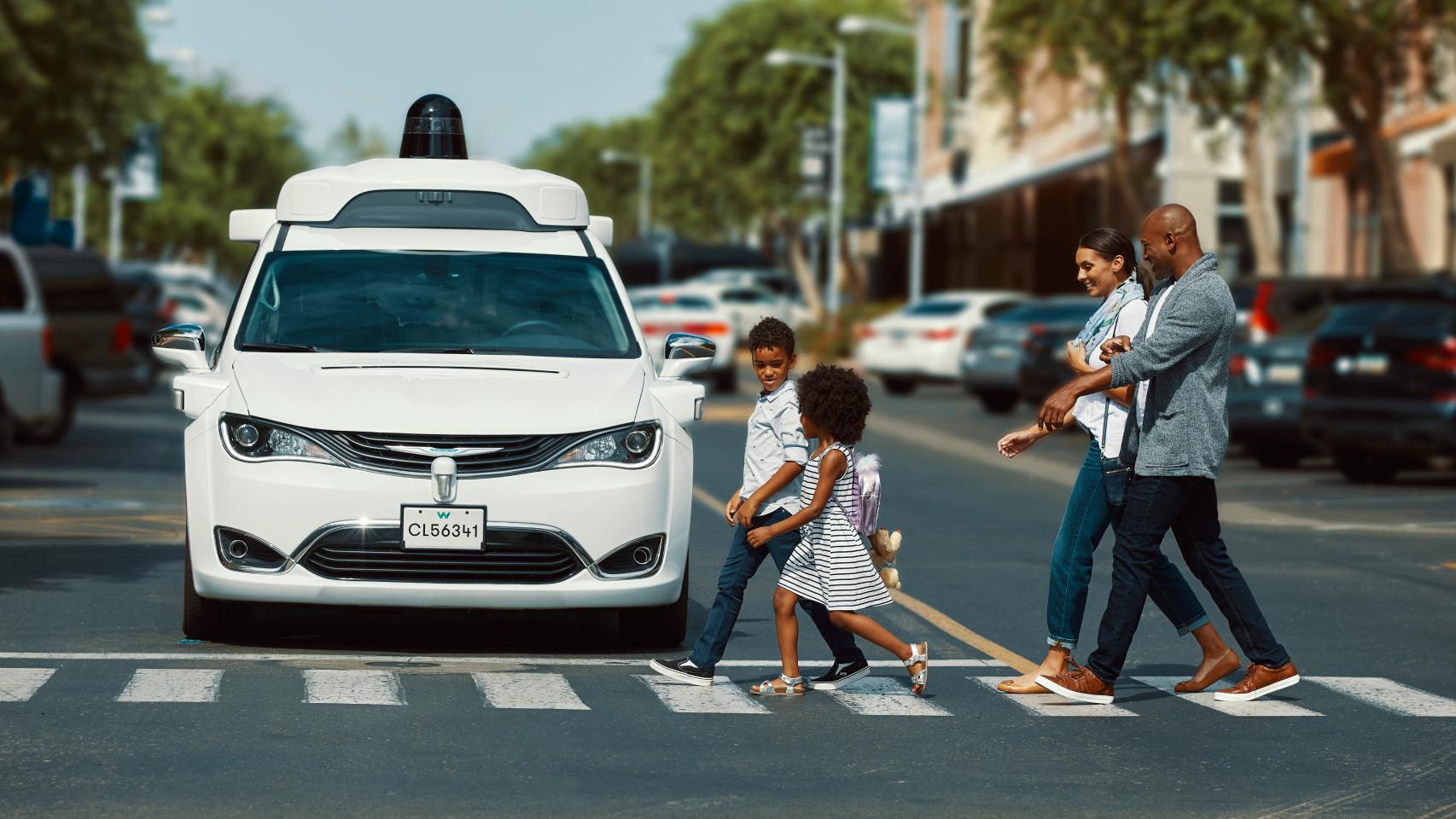 Un coche de Waymo en un paso de cebra con peatones.