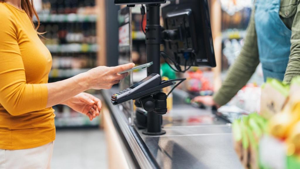 Imagen de ilustración de una mujer pagando con el móvil.