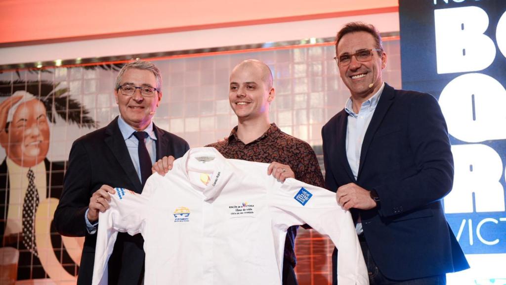 Francisco Salado y Antonio José Martín entregando la chaquetilla honorífica al cocinero Camilo Rojas.