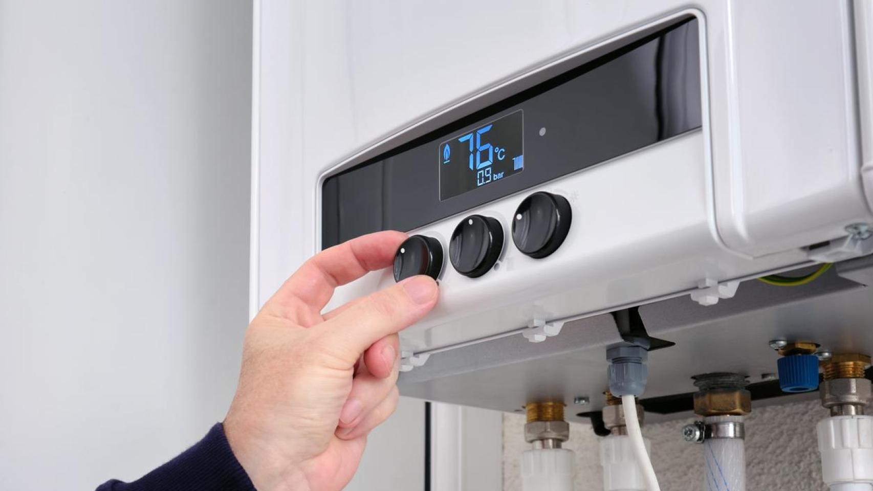 Una persona ajustando la temperatura de una caldera.