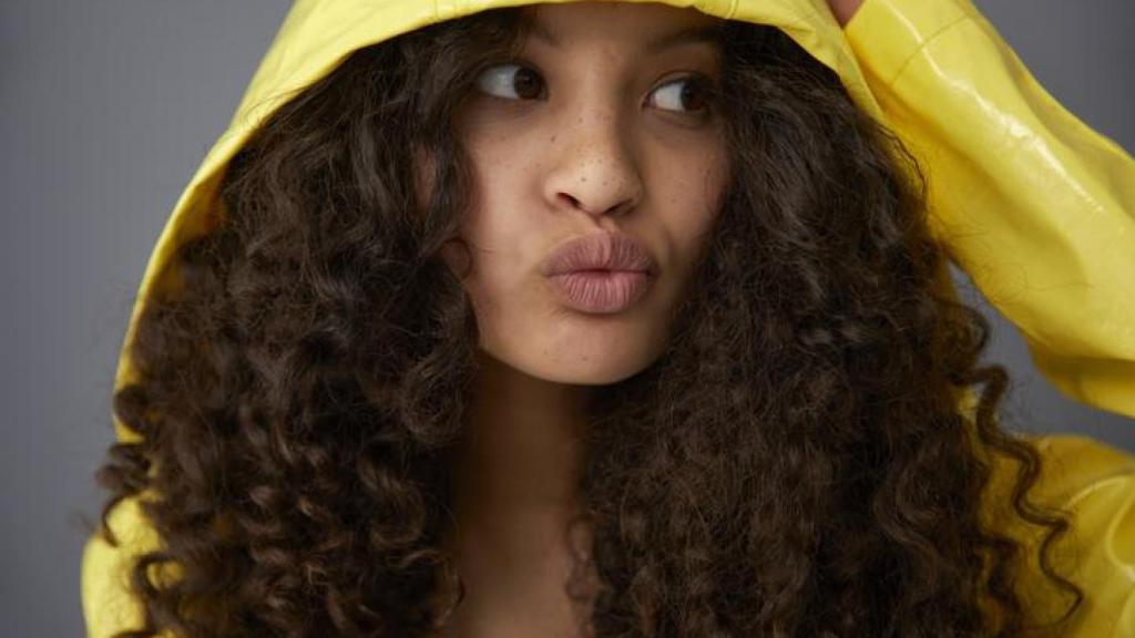 Mujer de pelo rizado con chubasquero.