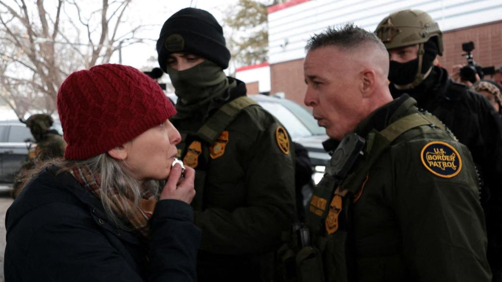 Una mujer soplando un silbato frente a agentes del ICE en Minneapolis.