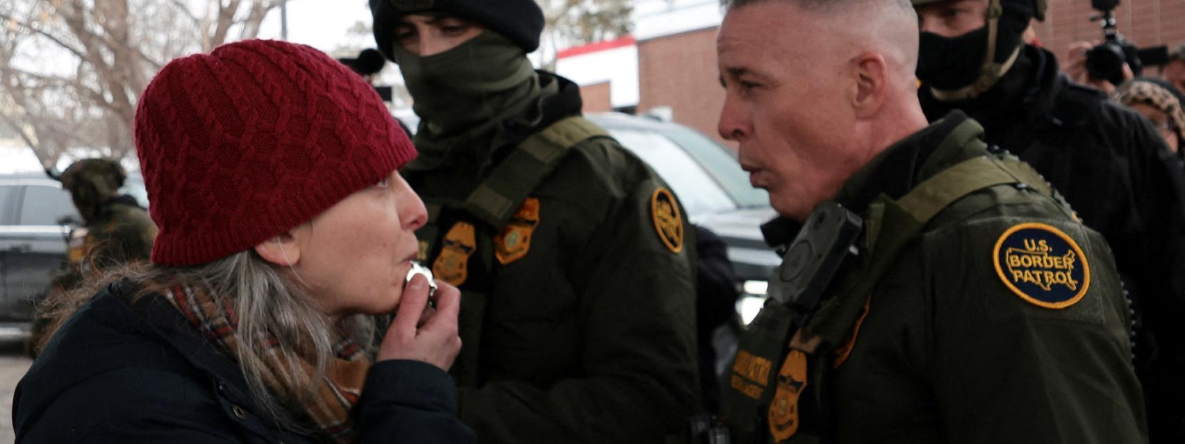 Una mujer soplando un silbato frente a agentes del ICE en Minneapolis.