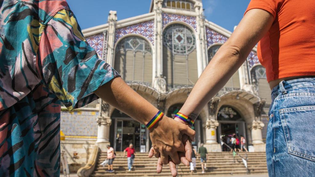 Dos personas se dan la mano frente al Mercado Central de Valencia. EE