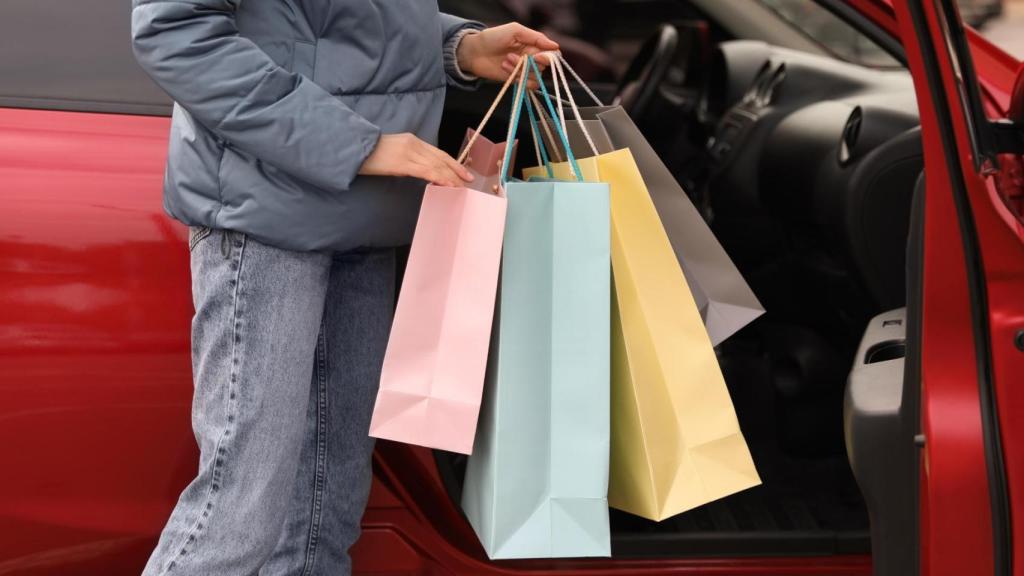 Una mujer coloca bolsas de la compra en el asiento del copiloto