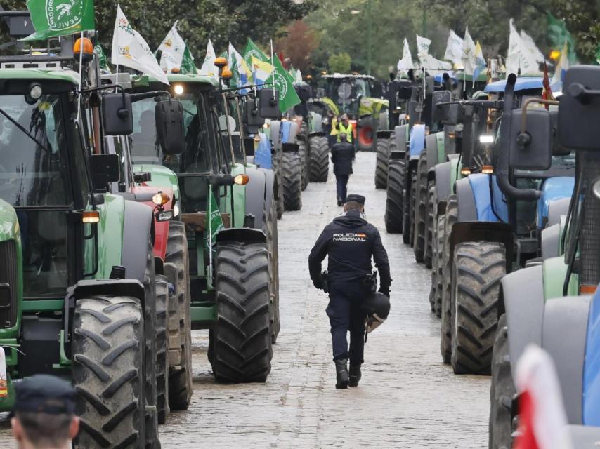 Un policía camina entre varios tractores mientras un grupo de agricultores participa en una movilización en Sevilla contra el acuerdo con Mercosur.