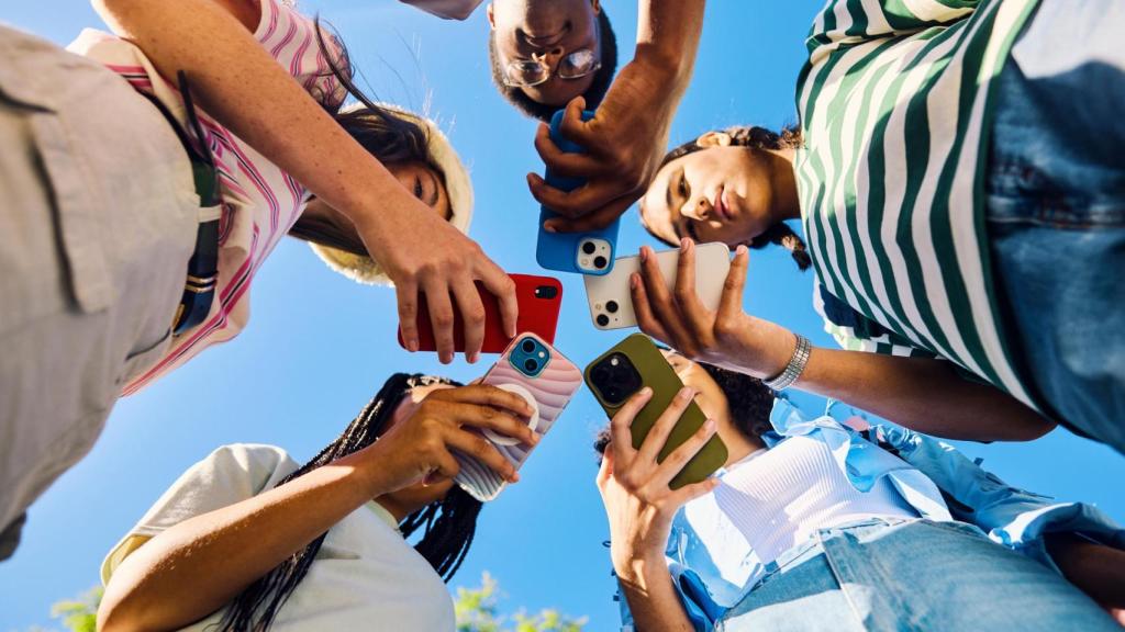 Grupo de adolescentes usando teléfonos juntos al aire libre.
