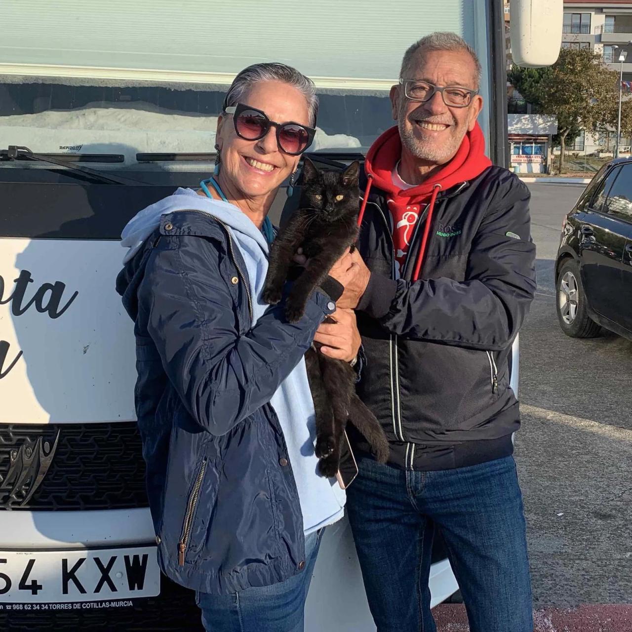 Charo y Carlos junto a su gato y de fondo su autocaravana.