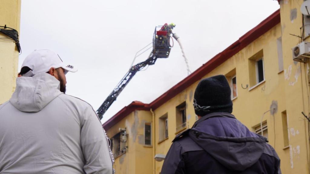 Los vecinos observan el trabajo de los bomberos este lunes en el edificio afectado.