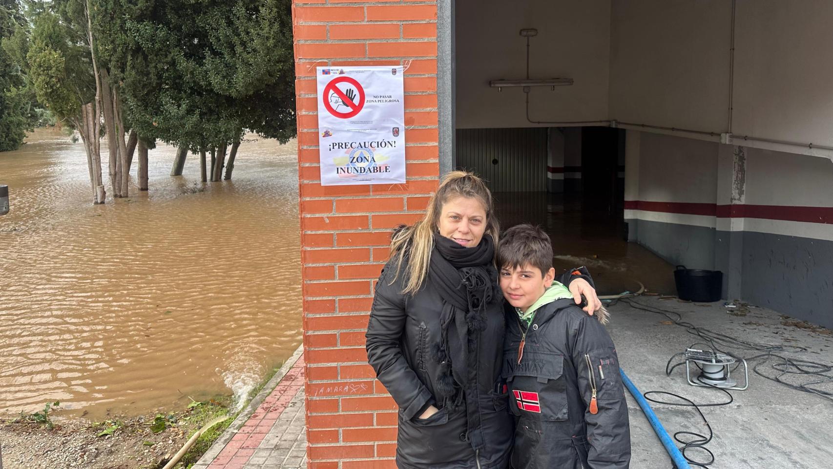 Verónica, vecina afectada por las inundaciones en Tudela de Duero, junto a su hijo en el garaje de su bloque y el río al lado.