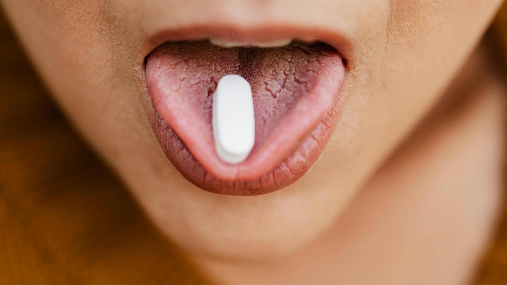 Una adolescente con un paracetamol en la lengua.