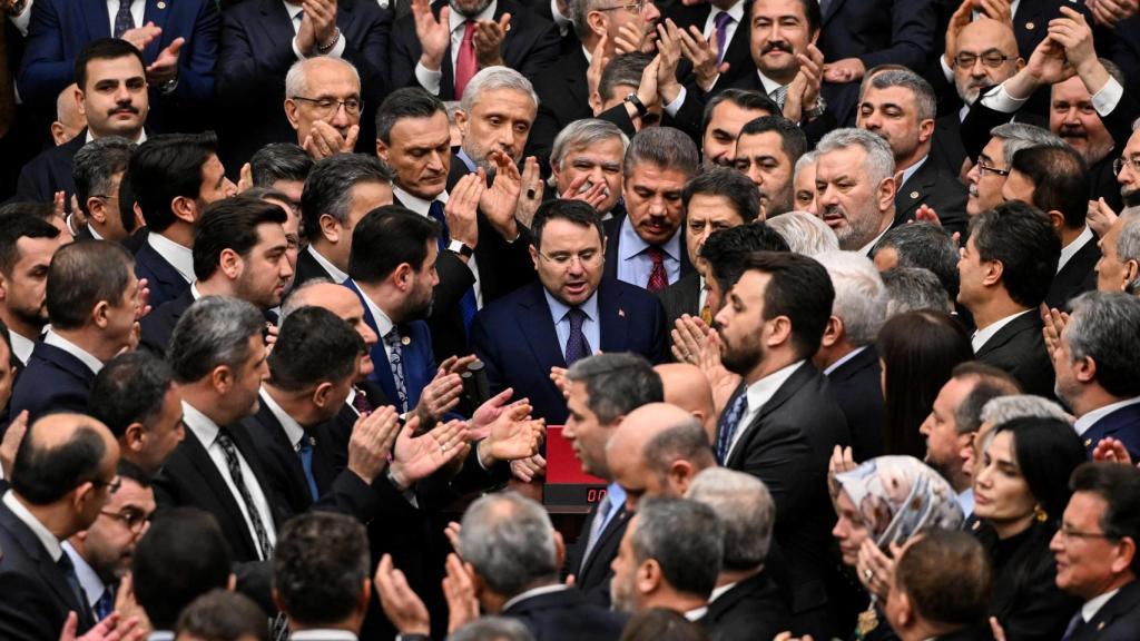 El recién nombrado ministro de Justicia de Turquía, Akin Gurlek, rodeado por legisladores del gobernante AKP, que lo protegen de los diputados protestantes del principal partido de la oposición.