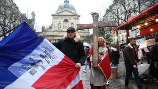 Un hombre sostiene una cruz de madera en la que se lee Ruega por Quentin y otro una bandera durante una manifestación de homenaje a Quentin, el estudiante de 23 años asesinado en Lyon.
