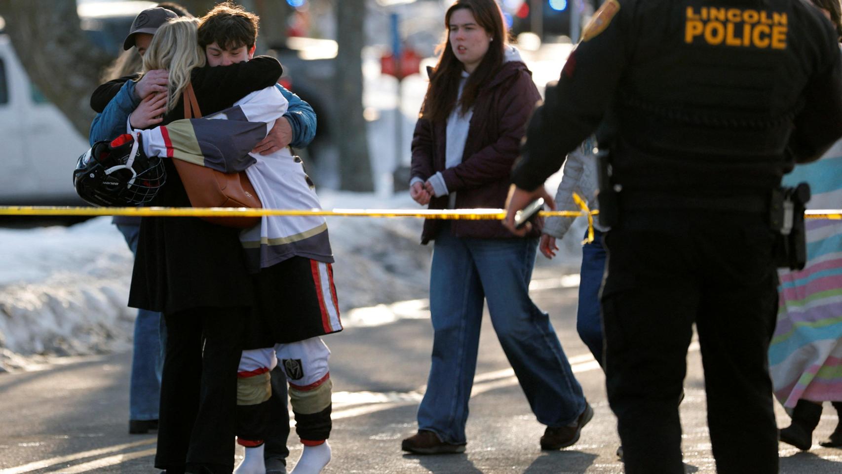 Un joven vestido con equipo de hockey se abraza a una persona a las puertas del Dennis M Lynch Arena, una pista de patinaje sobre hielo cubierta, después de un tiroteo en Pawtucket, Rhode Island, EE UU, el 16 de febrero de 2026