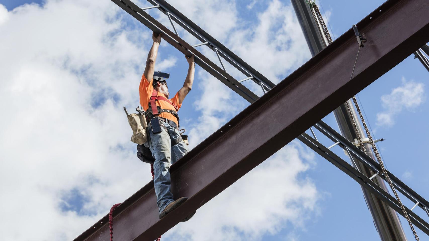 Trabajador de hierro en el sitio de construcción instalando vigas de techo.