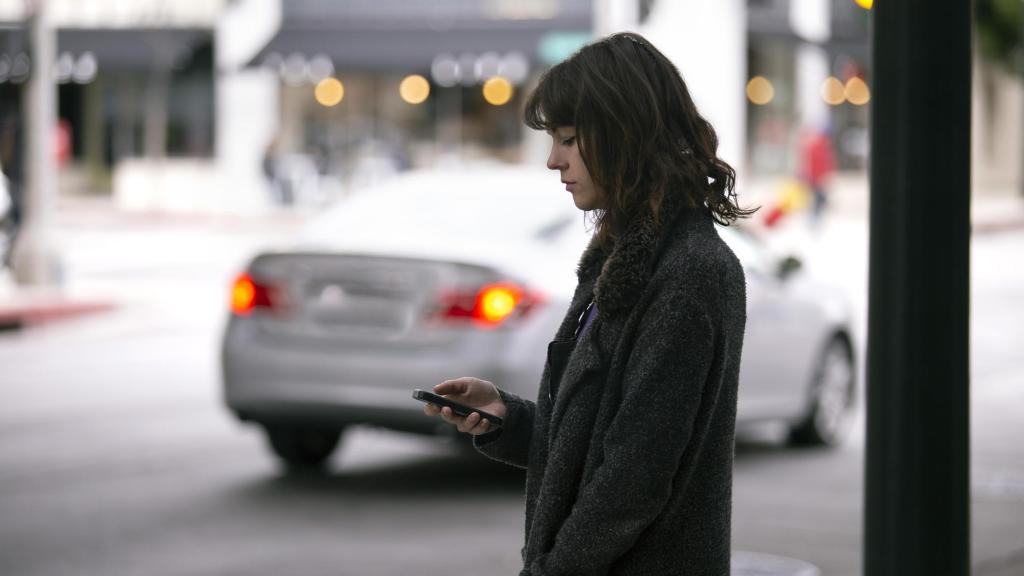 Una mujer espera la llegada de un taxi en una estación.