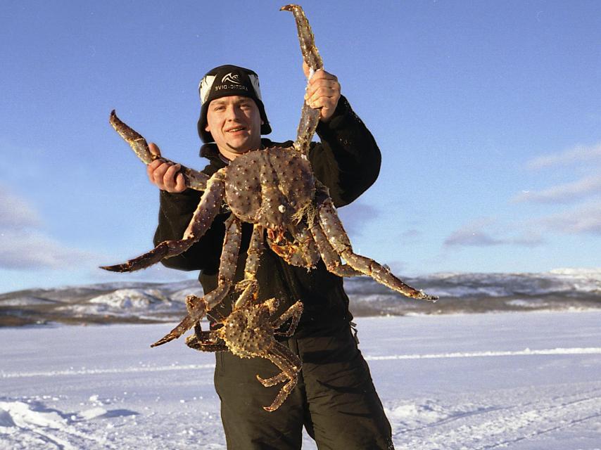 Un hombre con un cangrejo rey en sus manos.