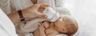 Un bebé tomando leche de un biberón.