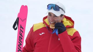 Oriol Cardona muerde la medalla de oro olímpica conseguida en los Juegos Olímpicos de Invierno de 2026.