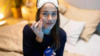 Mujer aplicándose crema Nivea.
