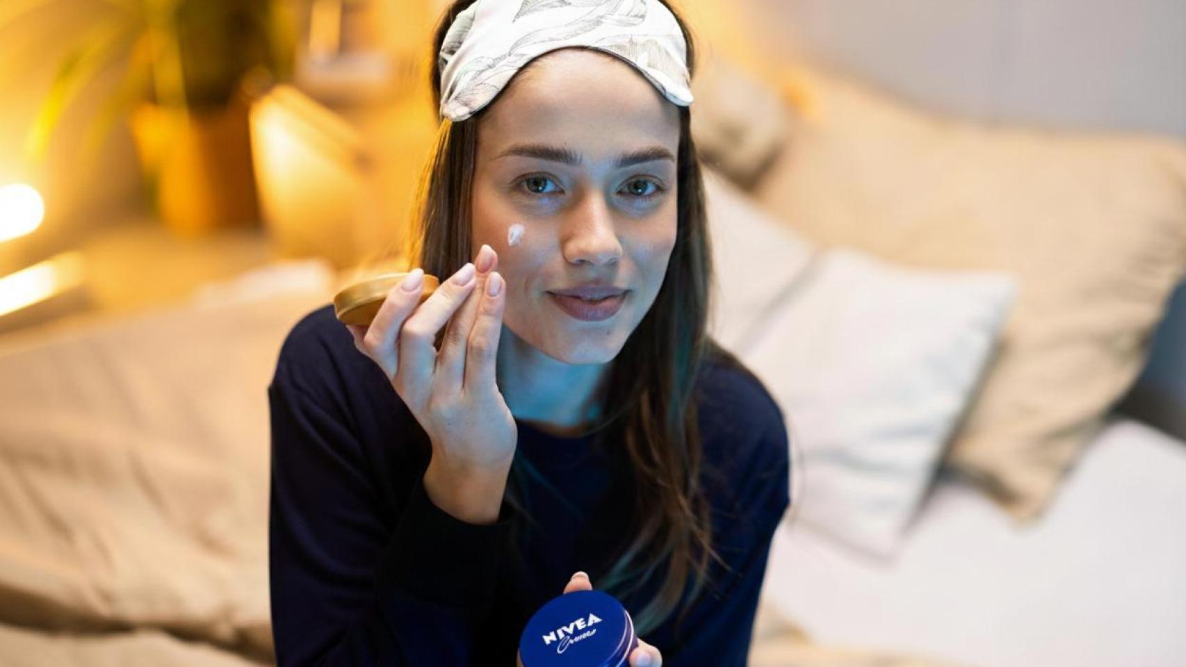 Mujer aplicándose crema Nivea.