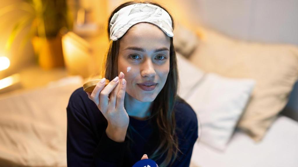 Mujer aplicándose crema Nivea.