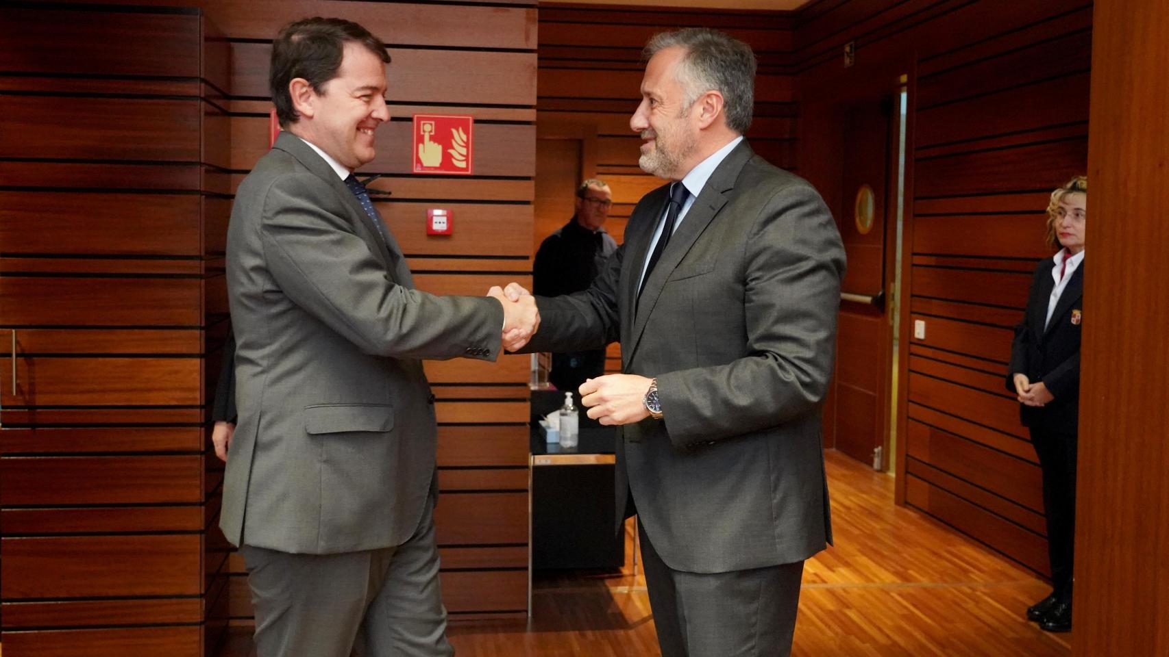 Alfonso Fernández Mañueco saluda a Carlos Pollán, a su llegada al hemiciclo para el Pleno de las Cortes de Castilla y León