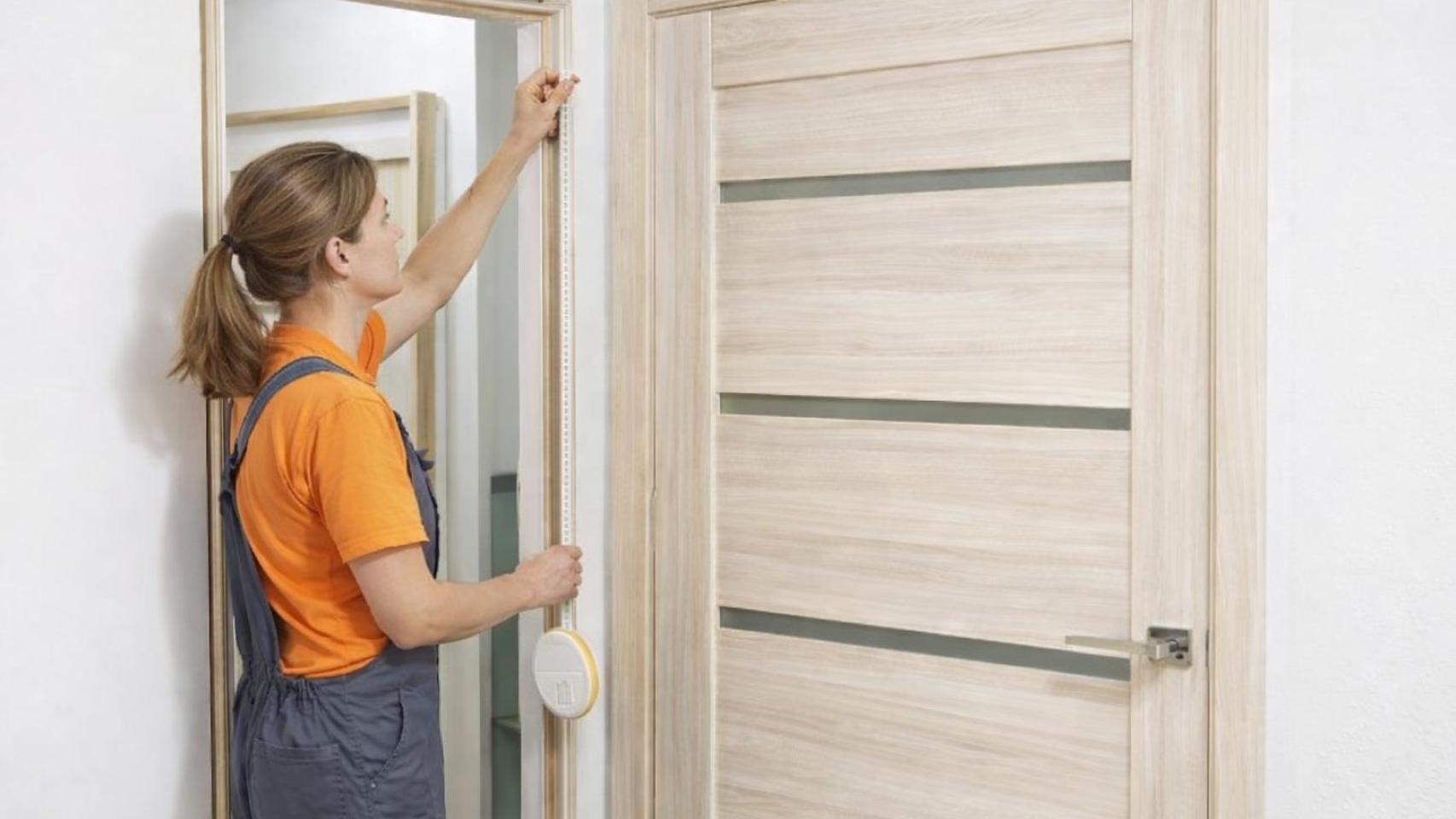 Una mujer colocando una cinta en la ventana.