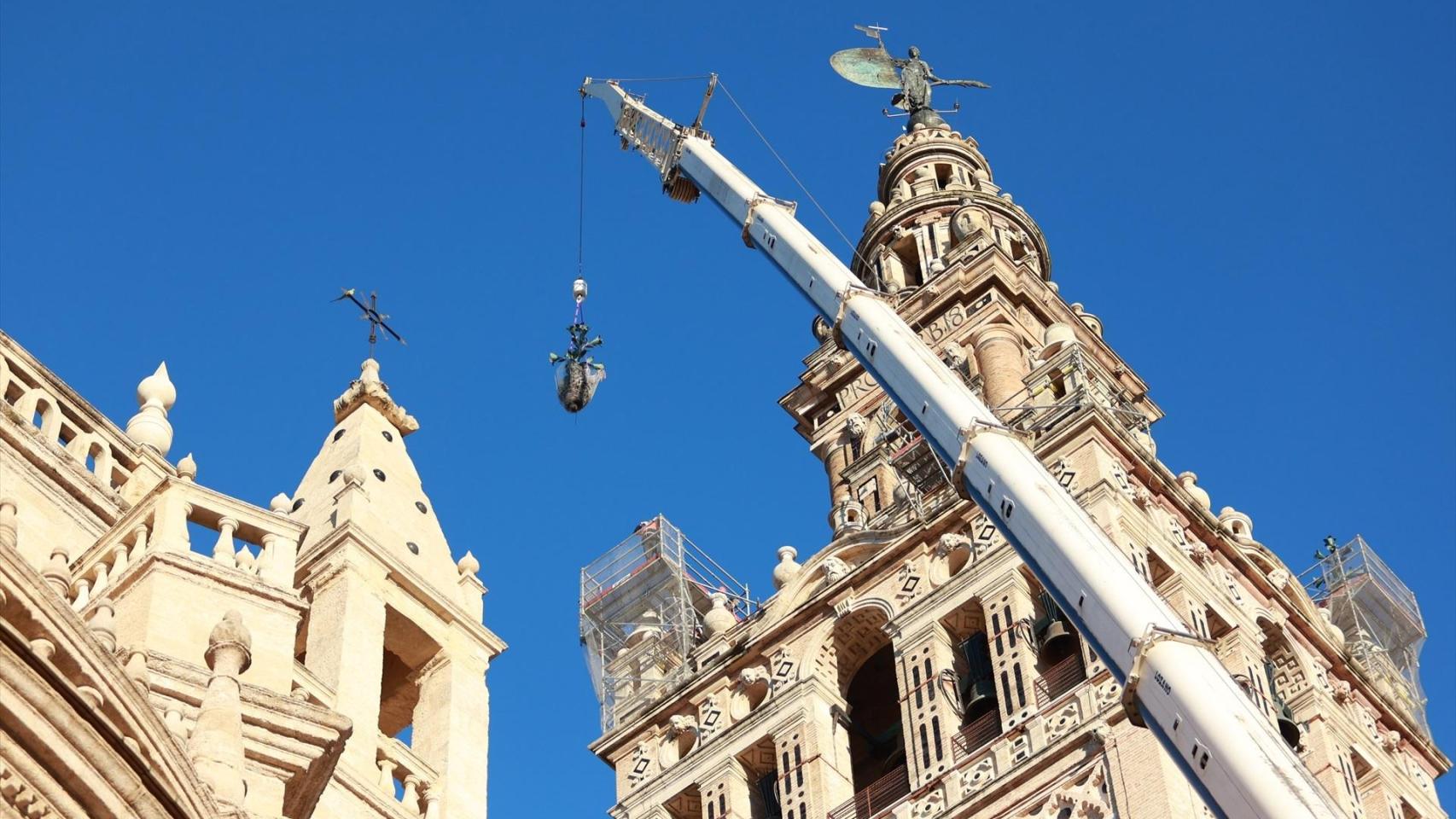 Los operarios retiran las azucenas que rematan las esquinas de la Giralda.