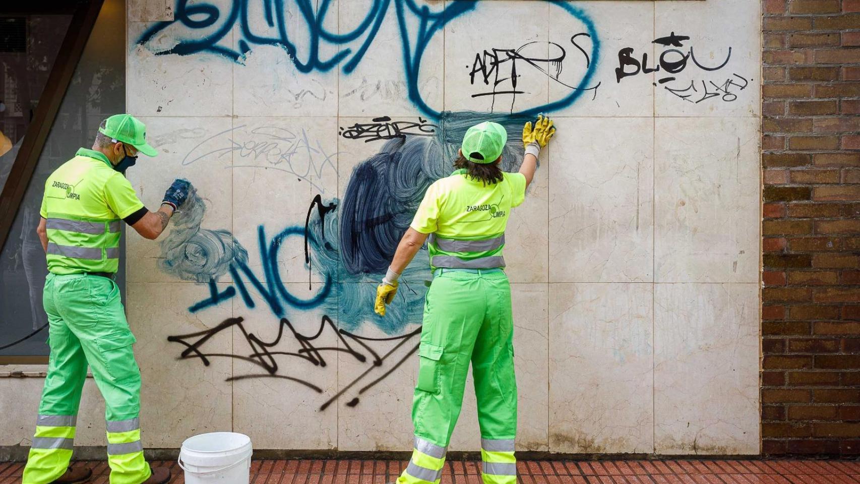Una brigada de limpieza del Ayuntamiento de Zaragoza limpiando un grafiti.