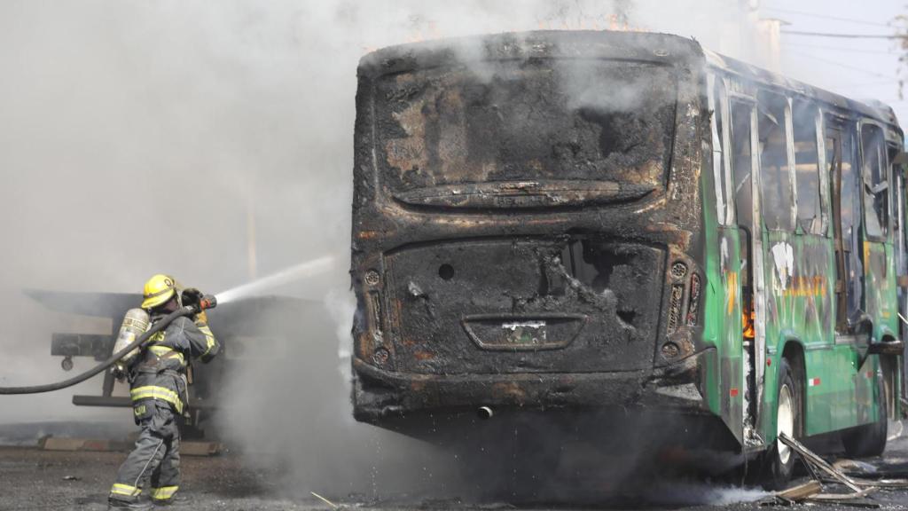 Un integrante del Cuerpo de Bomberos de Guadalajara intenta apagar un vehículo incendiado este domingo, en Guadalajara (México).