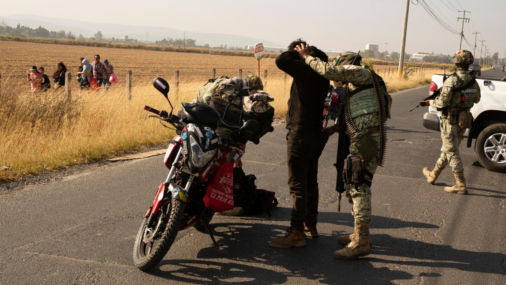 Soldados revisan a conductores de motocicletas después de que el crimen organizado quemara vehículos para bloquear carreteras tras el asesinato de 'el Mencho'.