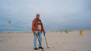 Un señor con un detector de metales buscando un tesoro en una playa