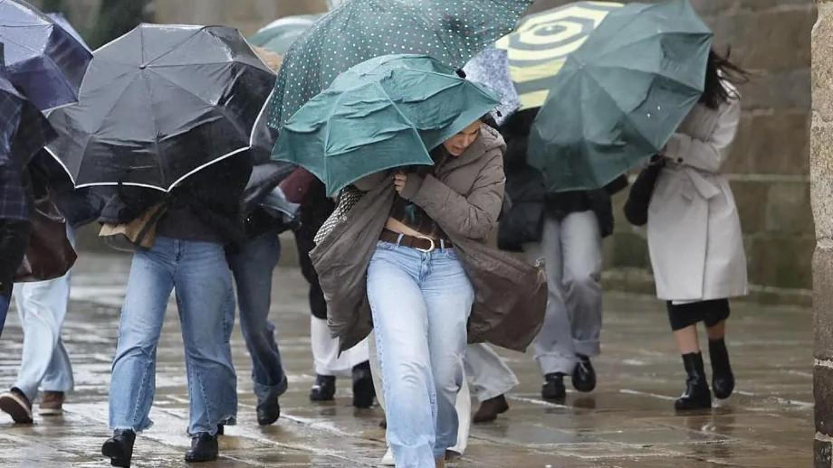 Varias personas se protegen de la lluvia y el viento en Santiago de Compostela.