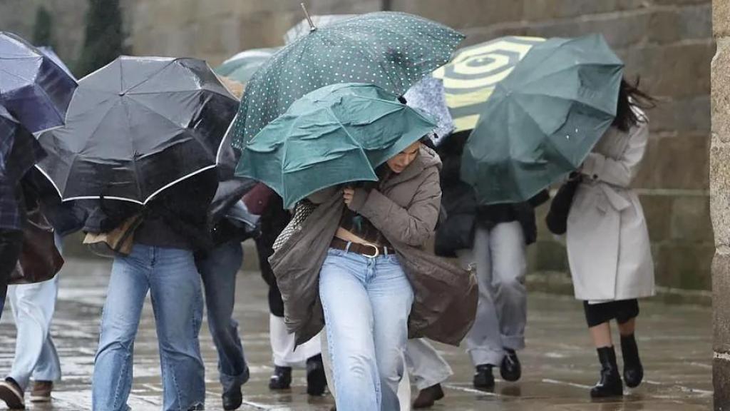 Varias personas se protegen de la lluvia y el viento en Santiago de Compostela.