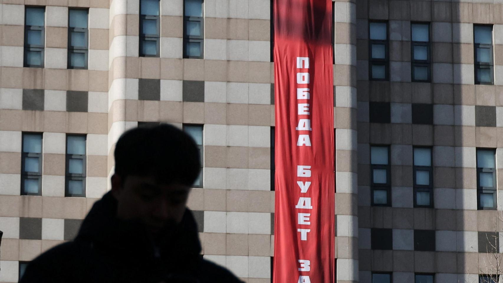 Un hombre camina frente a una pancarta que dice “La victoria será nuestra”, colgada en el exterior de la Embajada de Rusia.
