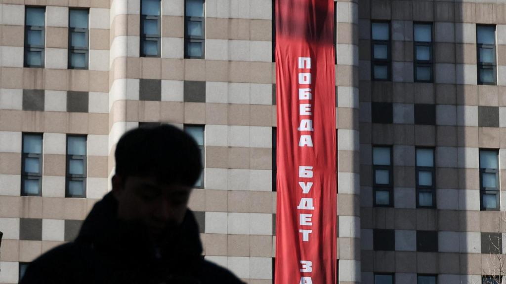 Un hombre camina frente a una pancarta que dice “La victoria será nuestra”, colgada en el exterior de la Embajada de Rusia.