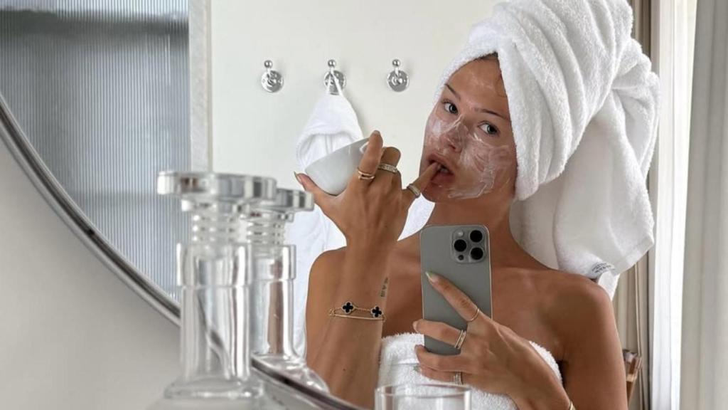 Mujer frente a la espejo con su rutina de cuidado facial.