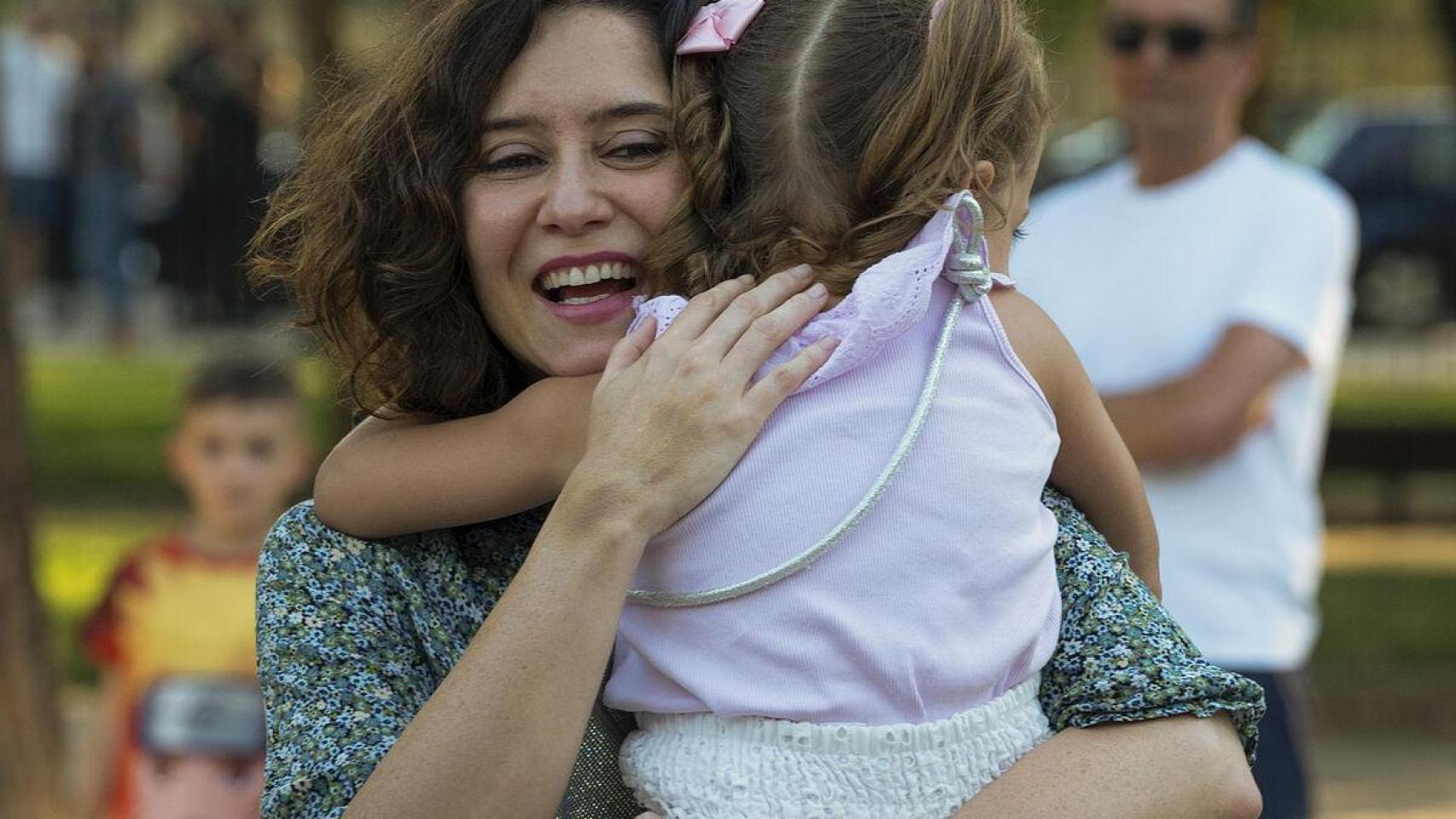 Isabel Díaz Ayuso abrazada a una niña tras un mitin.