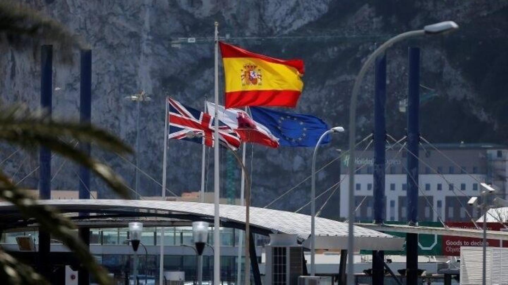 Las banderas de España, Reino Unido, Gibraltar y la UE, junto a la Verja que marca el paso a la colonia británica.