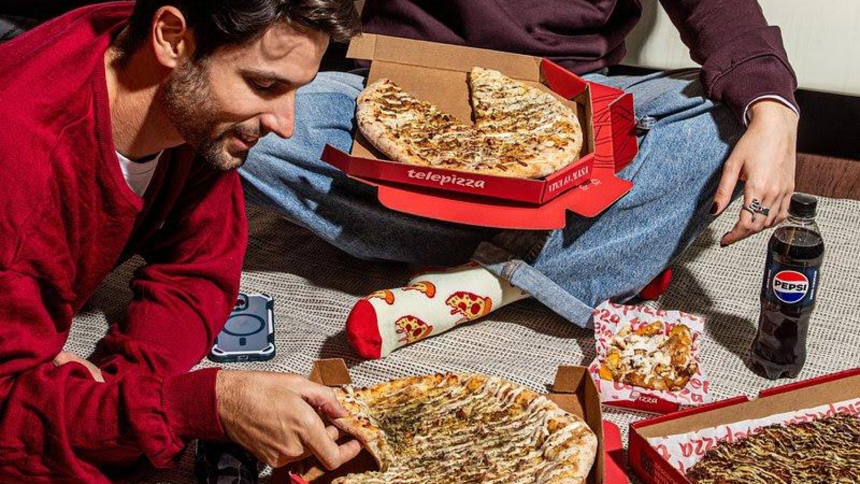 Dos personas disfrutando de pizzas de la cadena de Telepizza.