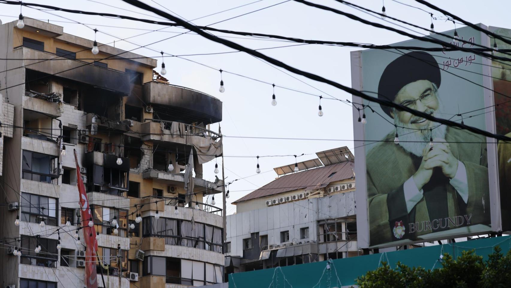 Un edificio en Beirut dañado por un misil israelí junto a un cartel de Hasán Nasralá, antiguo líder de Hezbolá.