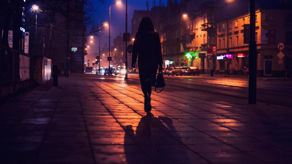 La silueta de la mujer que camina por la calle en la ciudad por la noche.