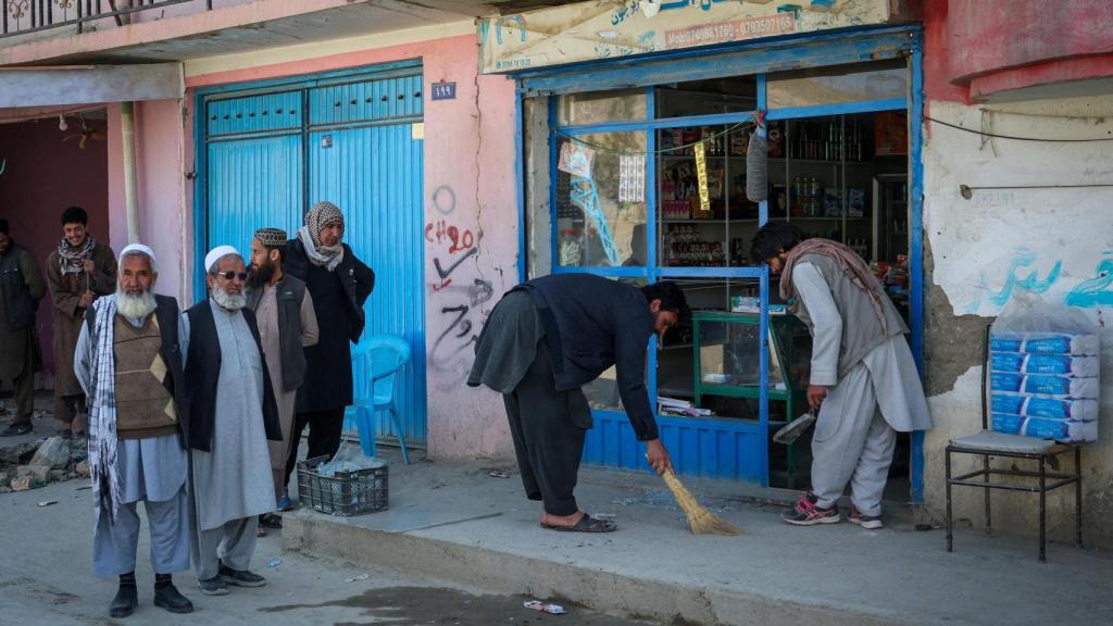 Neighbors of Darul Aman, near Kabul (Afghanistan), collect broken glass after the Pakistani bombing.