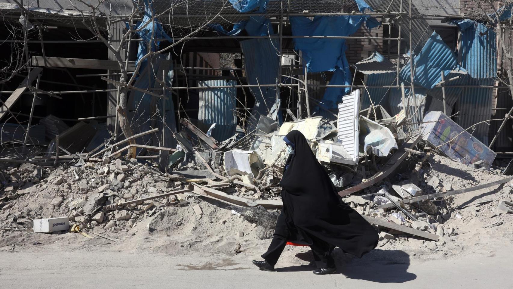 Una mujer iraní pasa por delante de los escombros de una comisaría de Policía bombardeada.